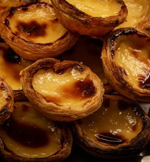 A tempting display of traditional Portuguese Pastel de Nata pastries, glistening with caramelized tops.